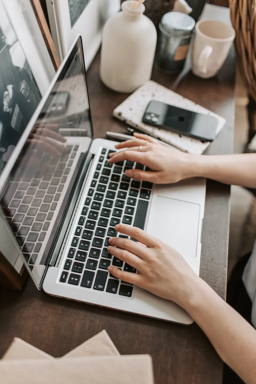 Vue du dessus d'une femme travaillant sur drupal en agence web et assise à table et tapant sur le clavier de l'ordinateur